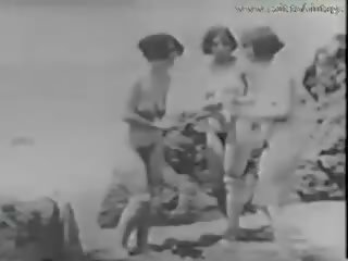 1928 vintāža ar a stripling spiegošana meitenes par the pludmale